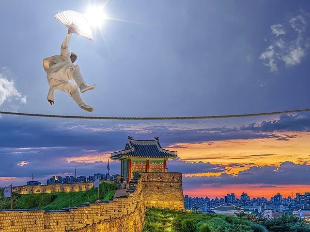 Un artista en el aire con un abanico, sobre una tradicional fortaleza coreana al atardecer.